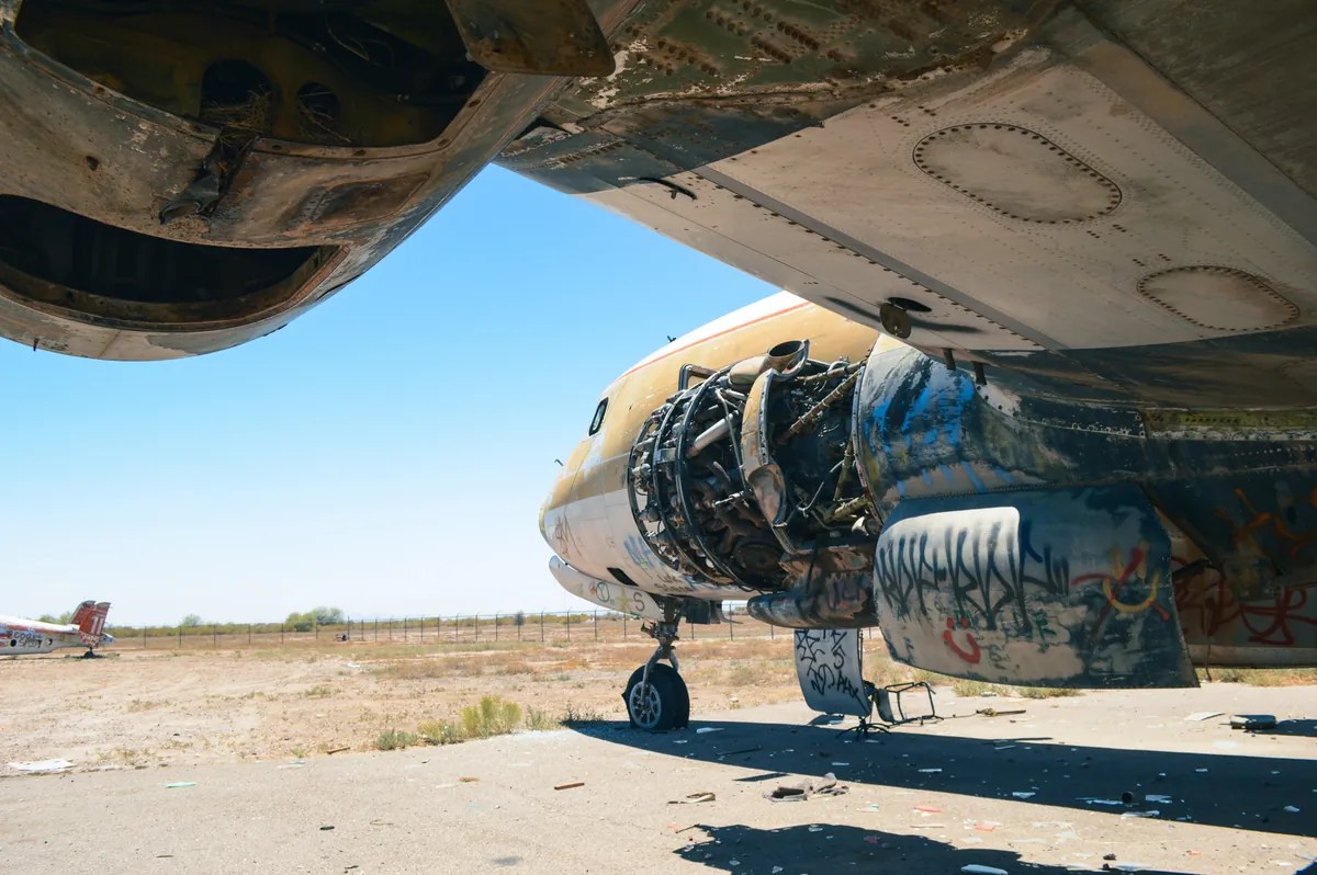 Abandoned aircraft covered in graffiti on a desert airfield