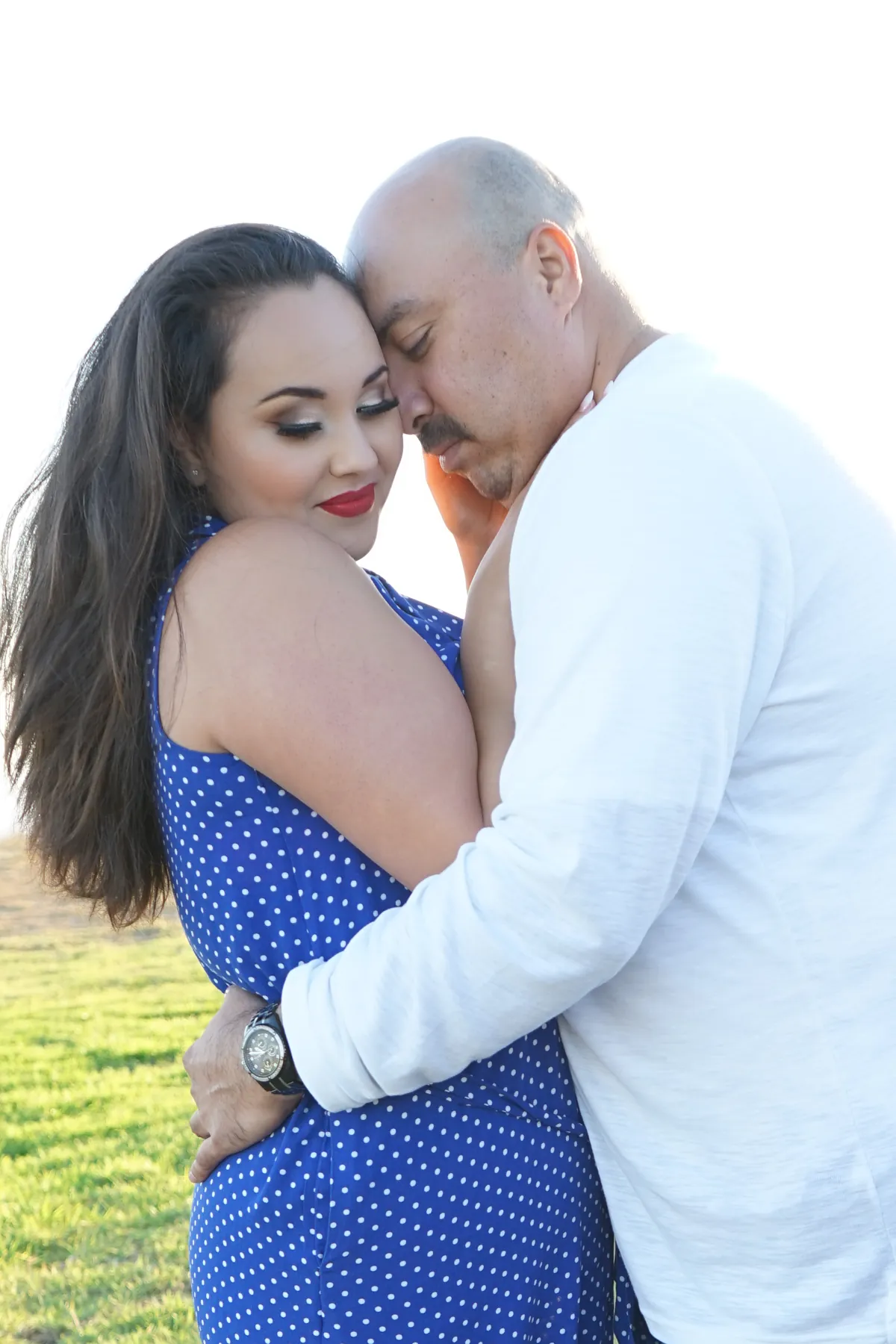 Couple in a tender embrace with eyes closed, lit by warm sunlight