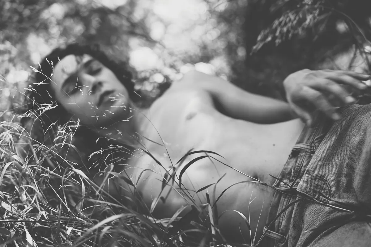 Black and white portrait of a person lying in tall grass