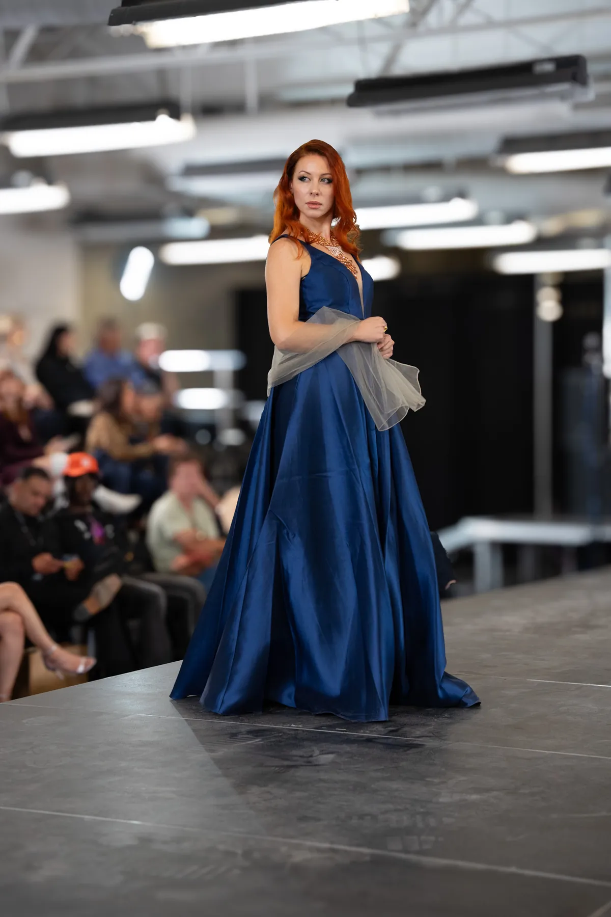 Model in a blue satin gown walking a runway