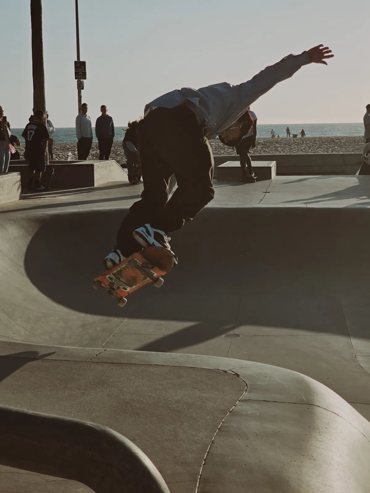 Skateboarder mid-trick on the lip of a skatepark bowl