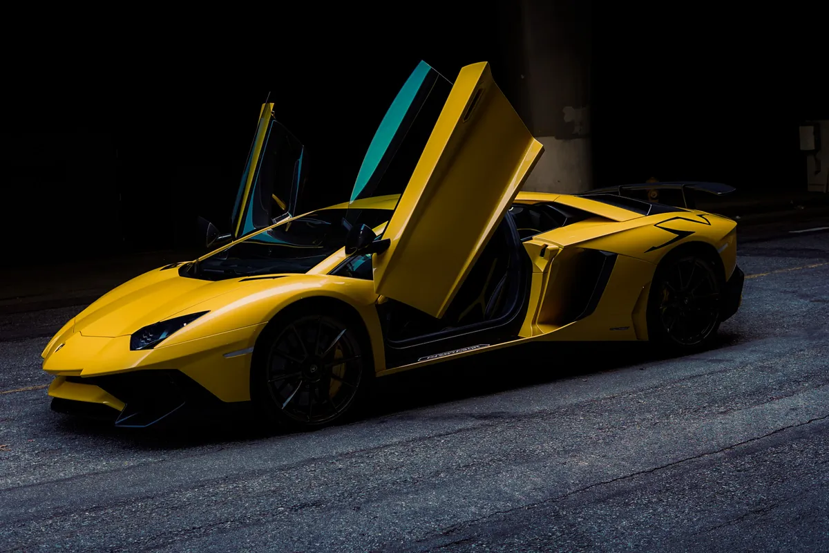 Yellow supercar with its scissor door raised against a dark background