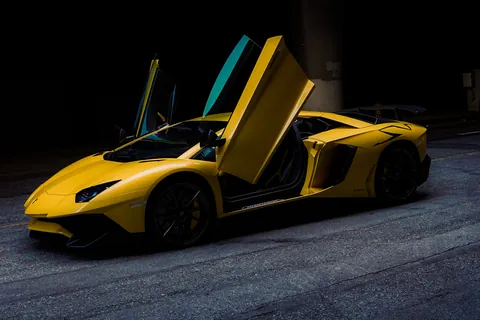 Yellow supercar with its scissor door raised against a dark background